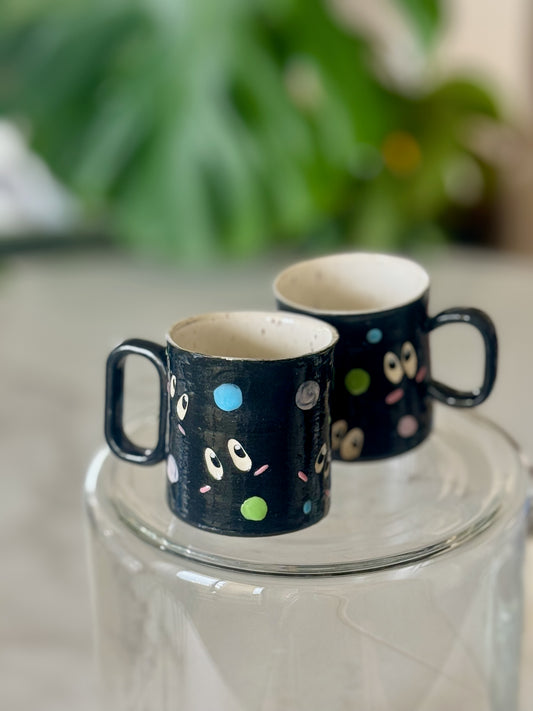 Two soot sprite espresso mugs side by side showing matching illustrated pattern