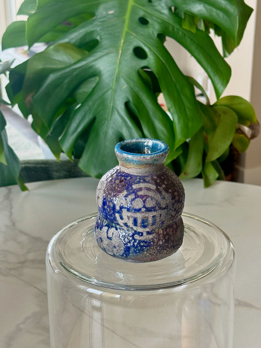 One Piece raku bud vase front view showing purple blue crystalline glaze and teal rim