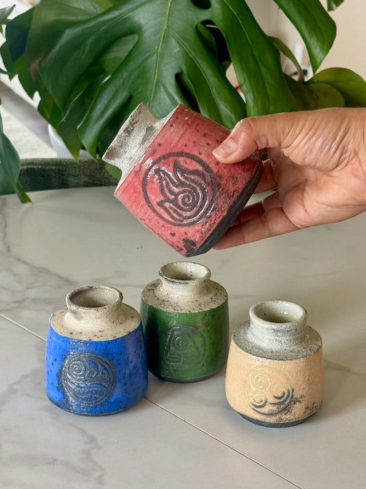 All four Avatar nation raku bud vases together showing Air, Water, Fire, and Earth symbols