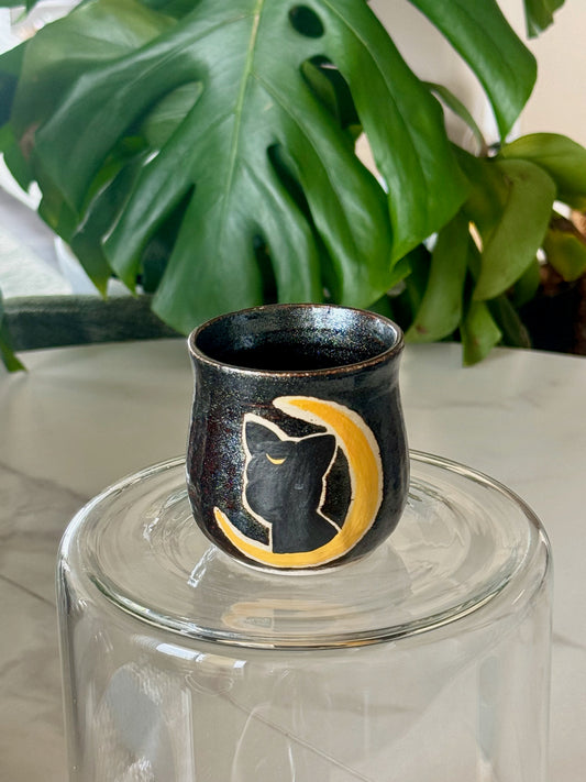 Luna cup showing black cat silhouette with golden crescent moon on deep dark glaze