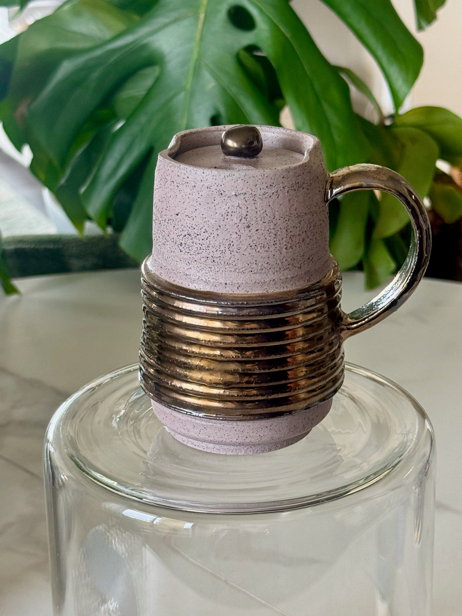 Locking travel mug front view showing coiled bronze band and speckled lavender glaze with lid
