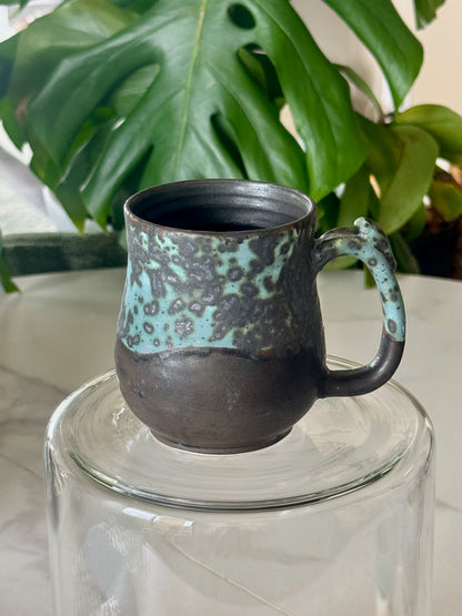 Teal spot glaze mug front view showing teal and mint spot pattern over dark clay body