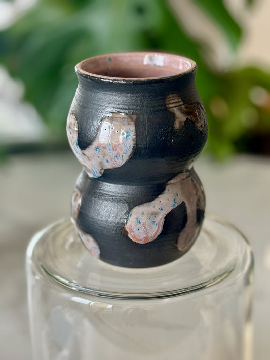 Abstract double-bubble vase front view showing matte black glaze with raised white and pink speckled patches