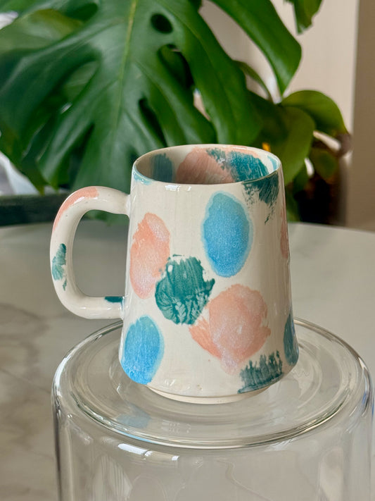Abstract dot mug front view showing blue, teal, and pink dot pattern