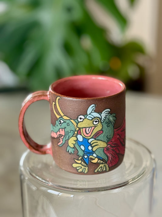 Frog Thor and Crocodile Loki Get Help mug front view showing full color illustration on brown clay