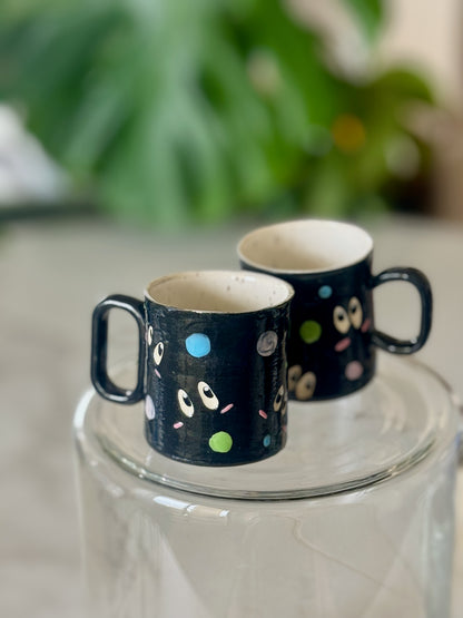 Two soot sprite espresso mugs side by side showing matching illustrated pattern