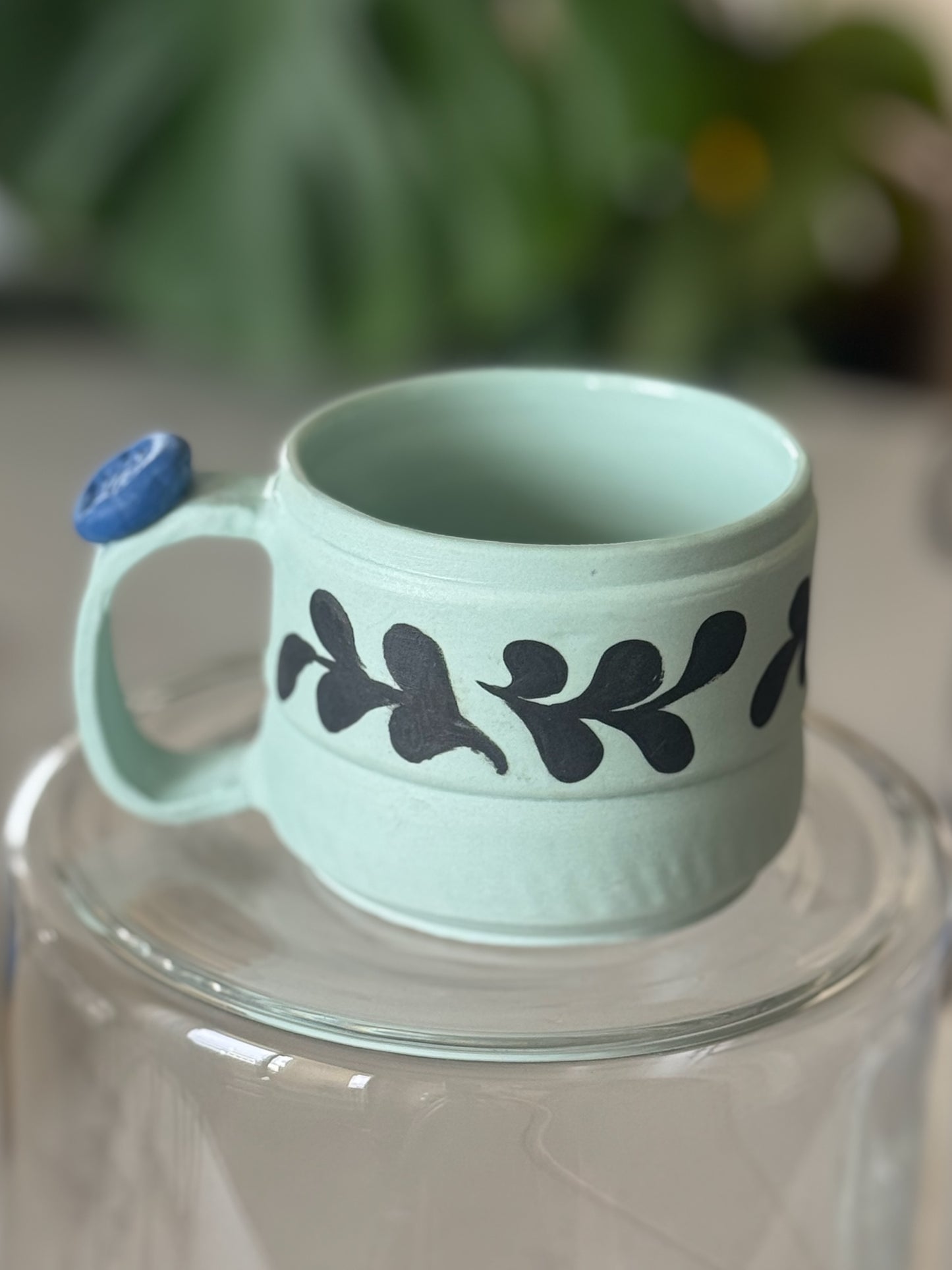 Botanical vine cappuccino mug front view showing mint green glaze and dark hand-painted vine band