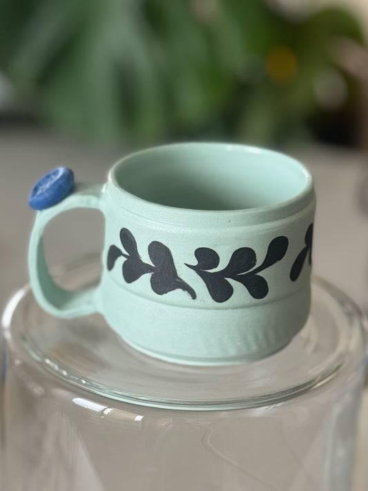 Botanical vine cappuccino mug front view showing mint green glaze and dark hand-painted vine band
