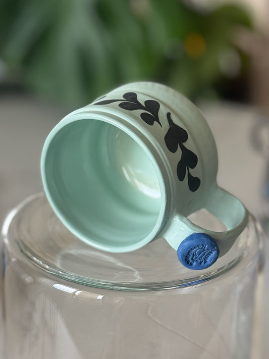 Botanical vine cappuccino mug bottom view showing blue frog stamp on handle and mint interior