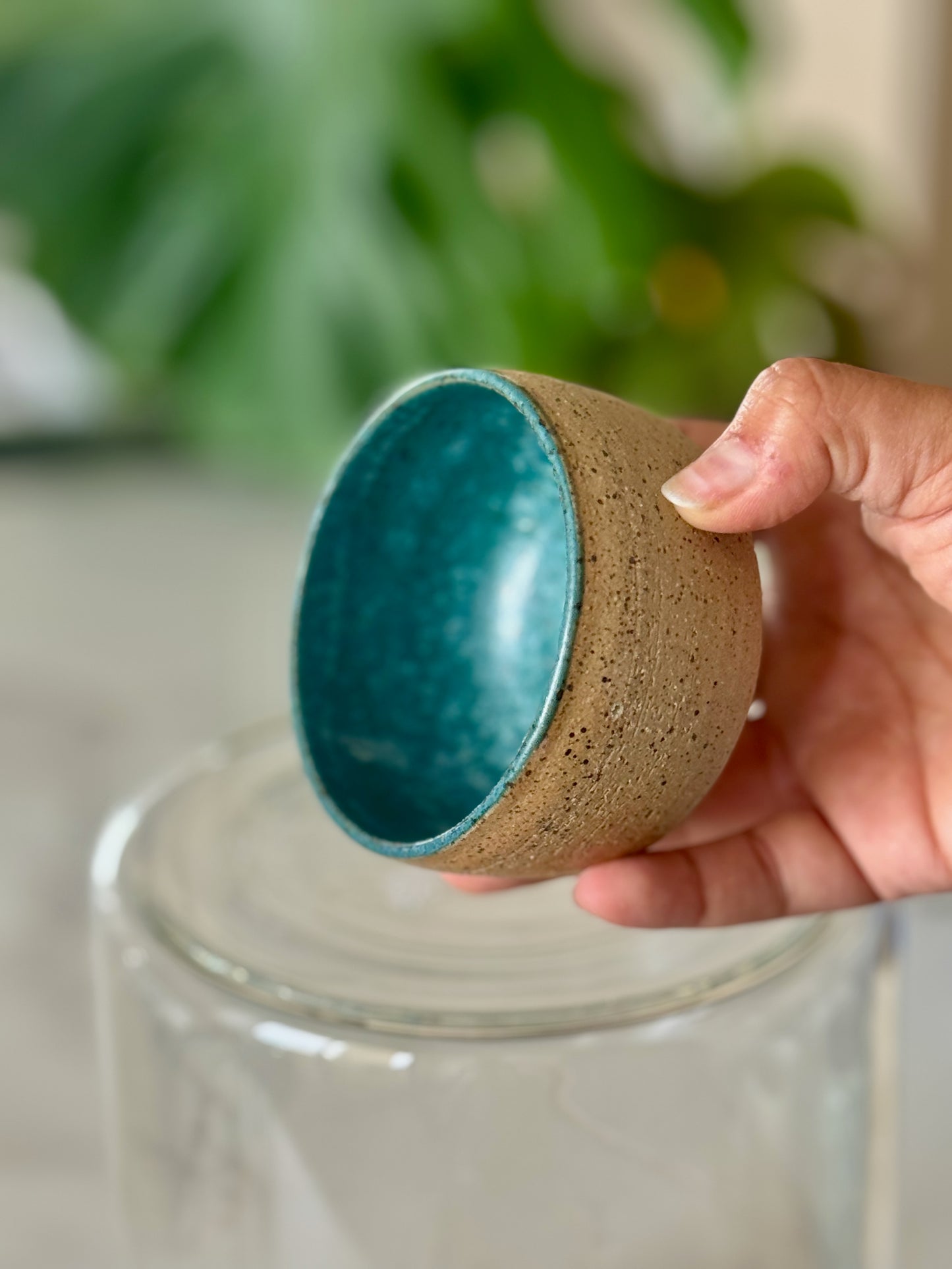Teal interior catch-all bowl held in hand showing size and teal glazed interior