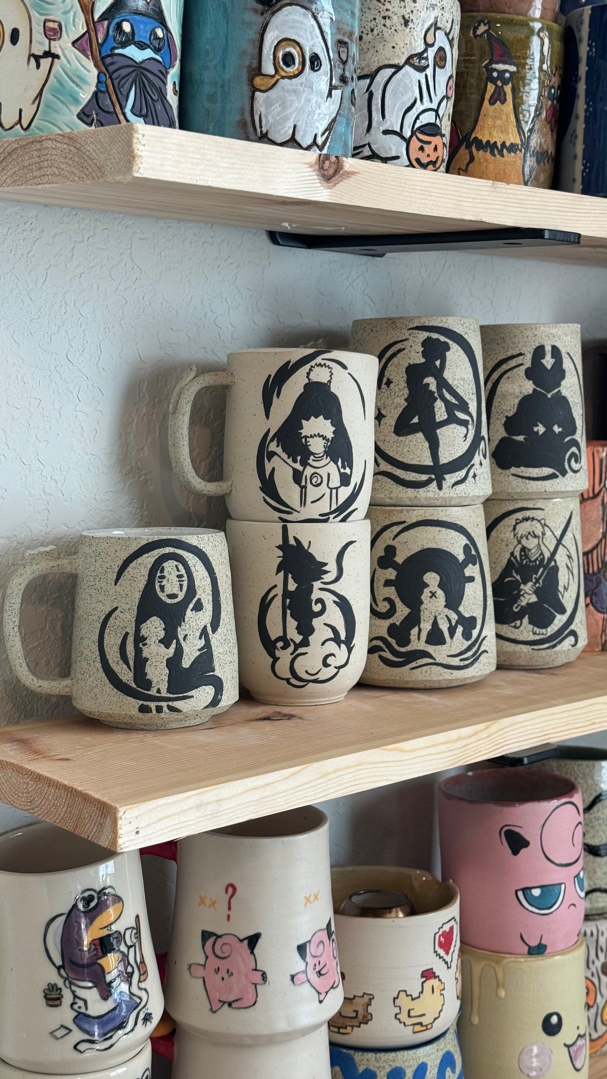 Collection of ceramic mugs with various designs on a wooden shelf.