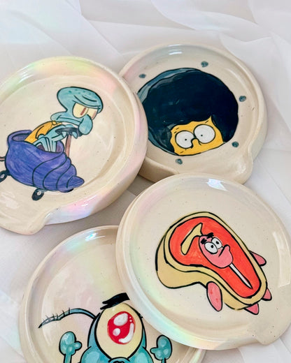 Set of ceramic plates with cartoon character designs on a white background